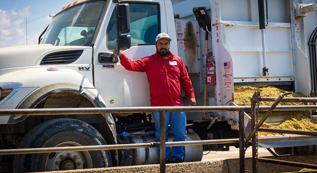 Man posing by the driver’s side door of a white feed truck