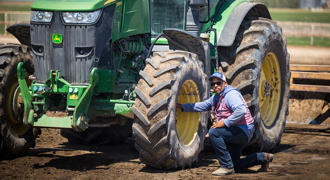 A man in sunglasses inspecting a large tractor