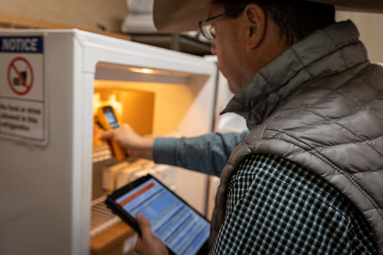 Man checking temperature in a refrigerator 